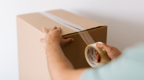 A person is wrapping the package with plastic tape.