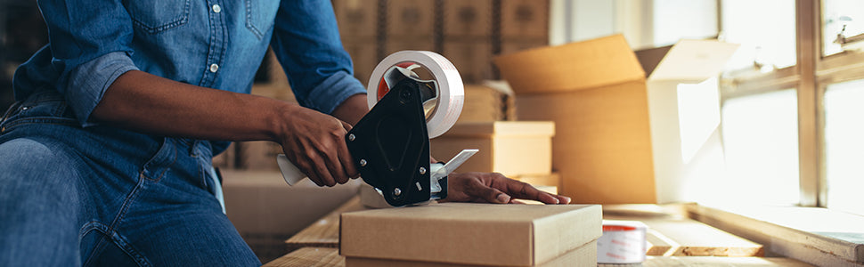 A warehouse worker is sealing a package with tape.