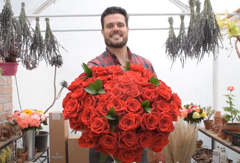 A man is holding a bouquet of red roses