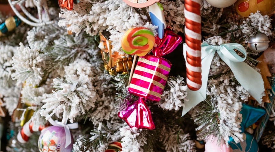 Christmas candies and gifts decorate a white-frosted Christmas tree