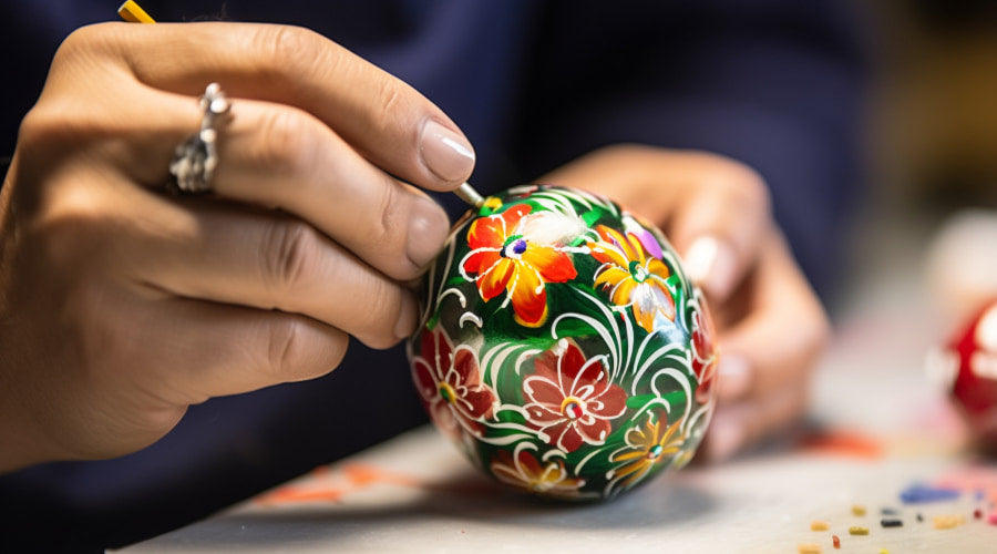 Close-up of hands painting floral designs on an Easter egg