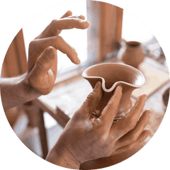 Potter's hands shaping clay on a wheel