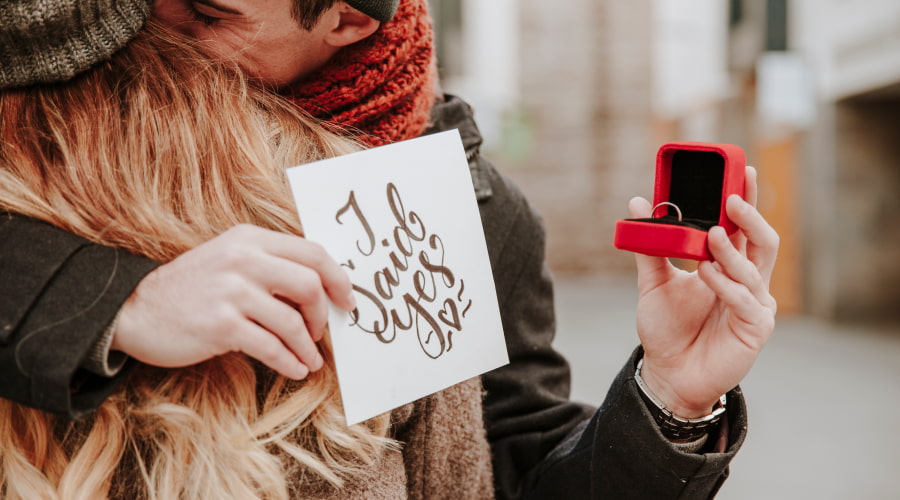 Couple embracing with a proposal note and ring