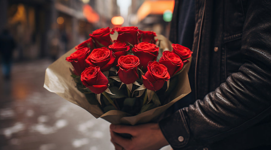 a man is holding red rose bouquet