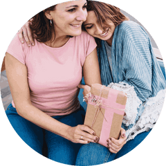 Two people smiling and embracing, one holding a wrapped gift with a pink ribbon.