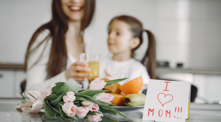 Mother and child at breakfast with "I Love Mom" note