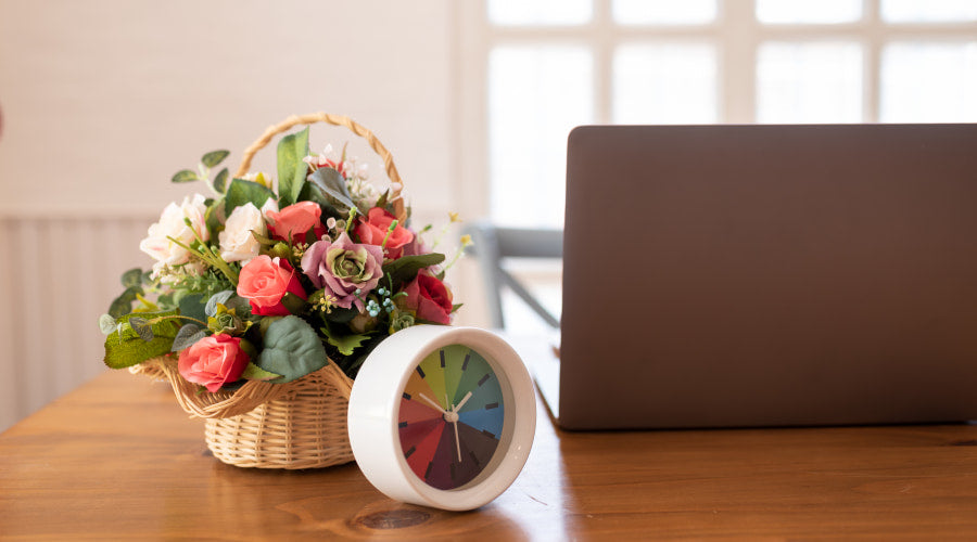 A colorful floral arrangement beside a laptop