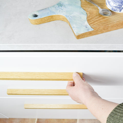 Oak drawer pulls, long wooden handles on a white kitchen with light grey worktop