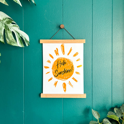 hello sunshine text inside a sun print, in magnetic poster hanger on a green wall