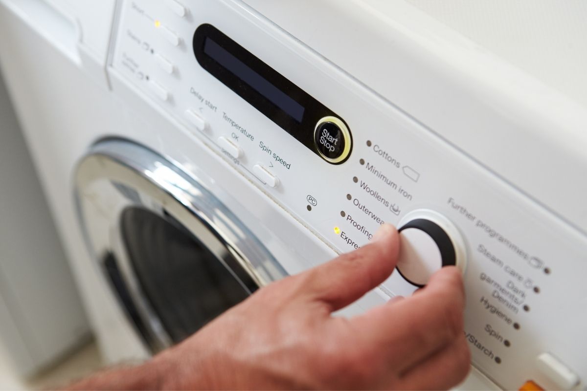 close up of a hand setting the cycle of a washing machine