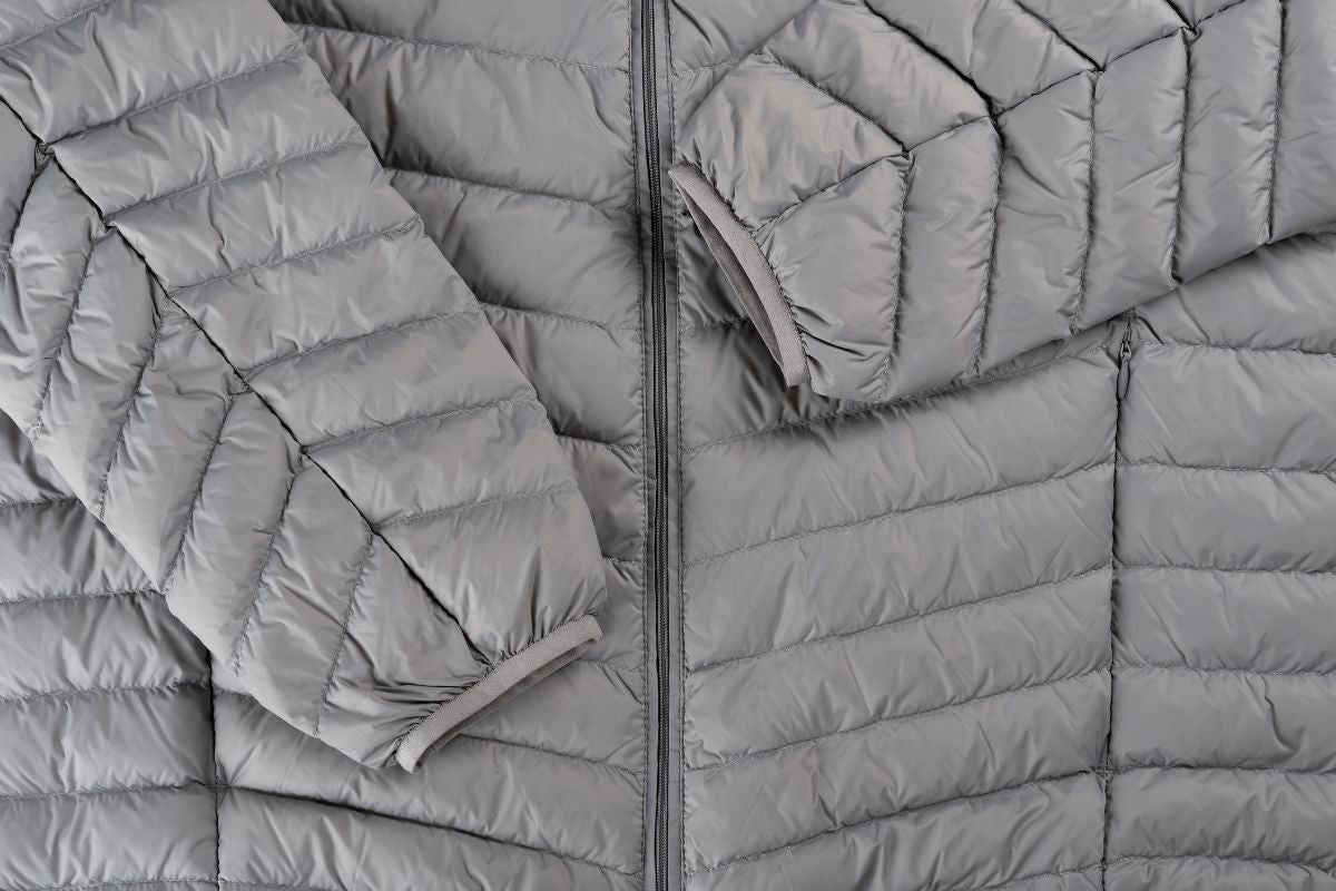 grey duck down jacket laid flat with arms folded over 