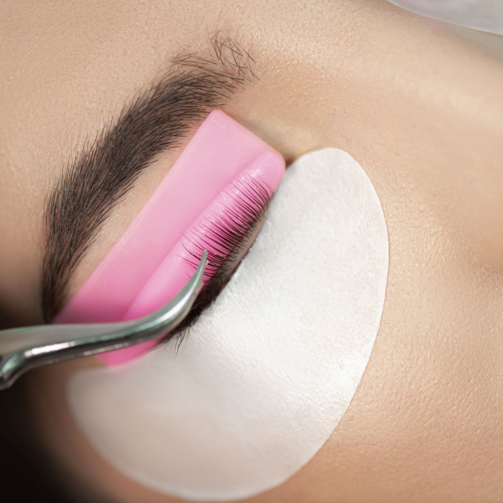 Person receiving an eyelash lift. The lashes are curled over a silicon rod and covered in a setting lotion