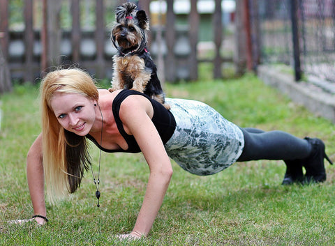 woman doing push ups with a dog on her back