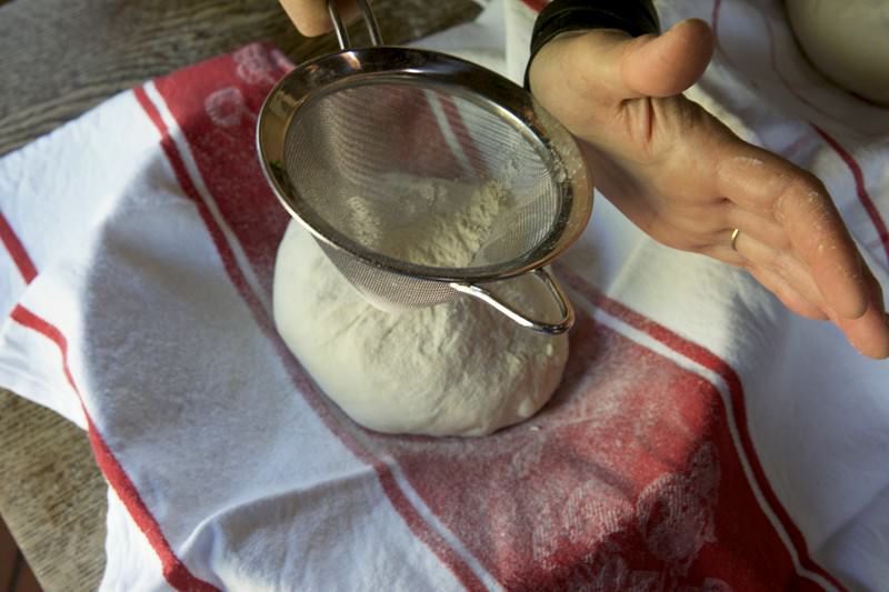 Sprinkle bread dough with flour to be baked in the Fontana wood-fired oven