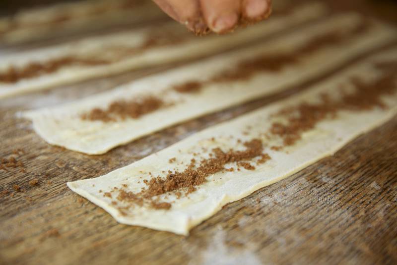 Putting brown sugar on puffed pastry to be placed in fontana wood-burning oven 