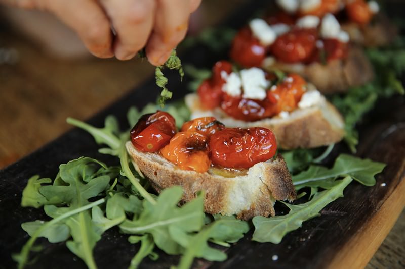 garnishing cherry tomato crostini with basil made in fontana oven