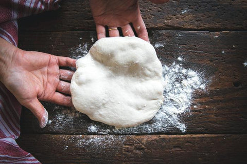 Person kneading pizza dough in hands