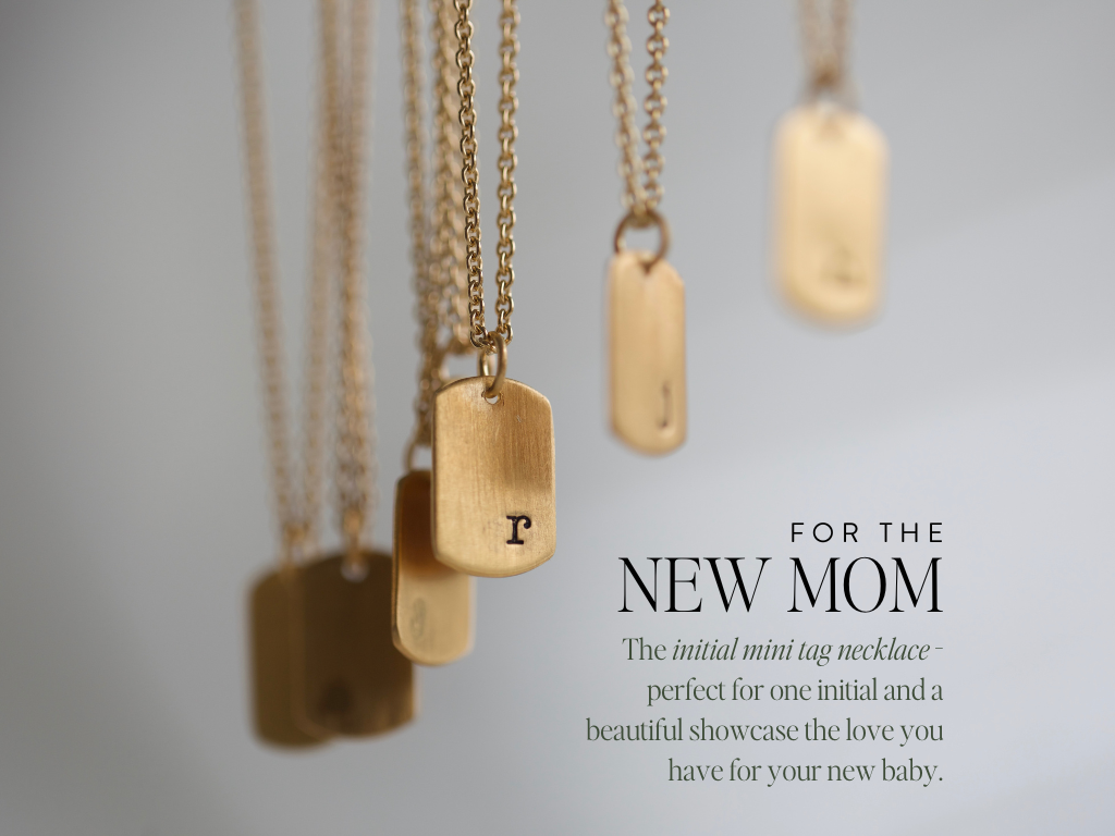 gold necklaces hanging with initials stamped on them. text on image reads : for the new mom, The initial mini tag necklace - perfect for one initial and a beautiful showcase the love you have for your new baby.