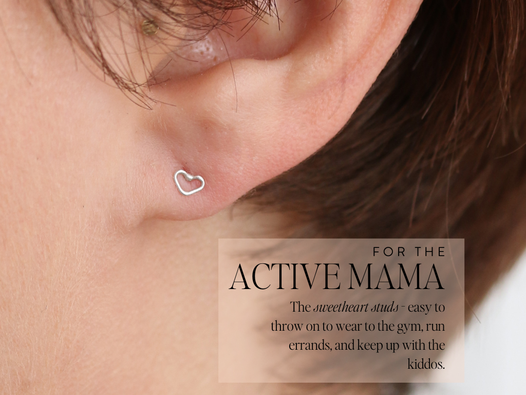 woman with short cropped haircut wearing tiny silver heart stud earrings. text on image reading : for the active mama, T﻿he sweetheart studs - easy to throw on to wear to the gym, run erran﻿ds, and keep up with the kiddos.