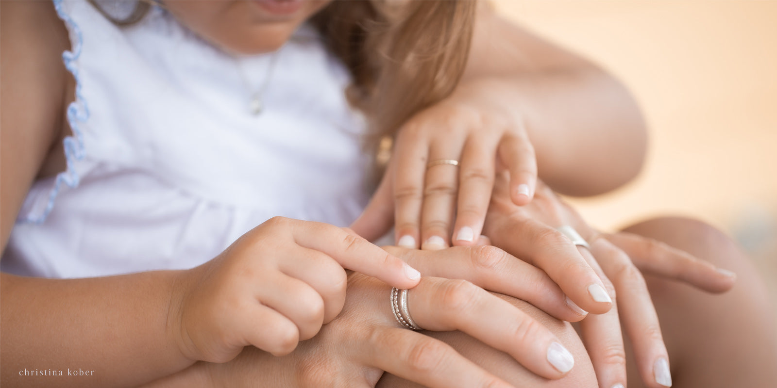 small girl in mother's arms touching mother's ring stack with index finger
