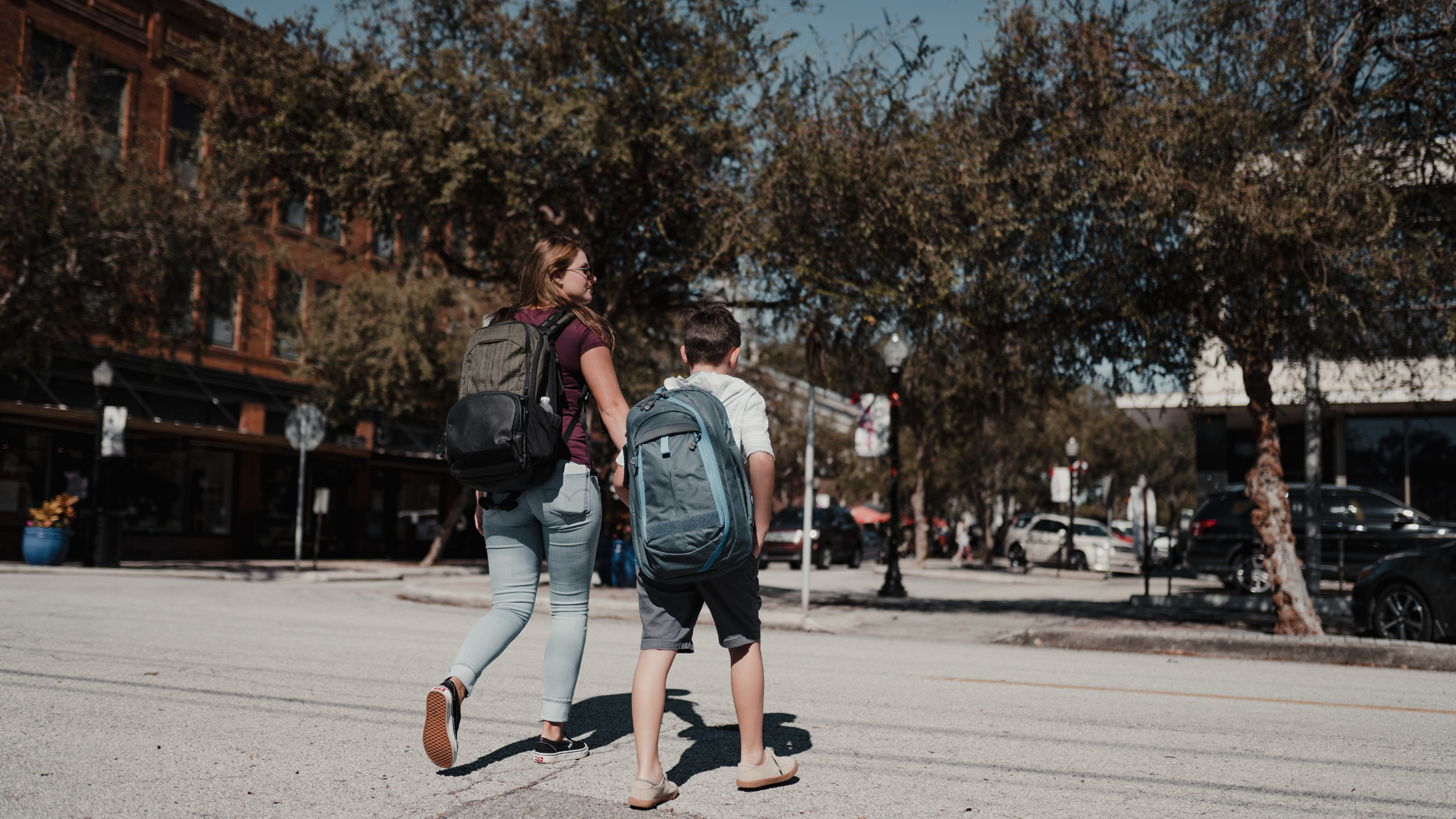 kids walking across the street to school wearing backpacks