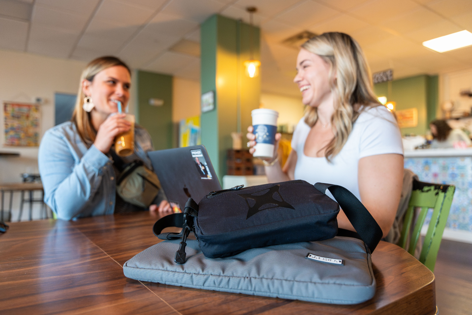 women in coffee shop with bulletproof laptop case and fanny pack