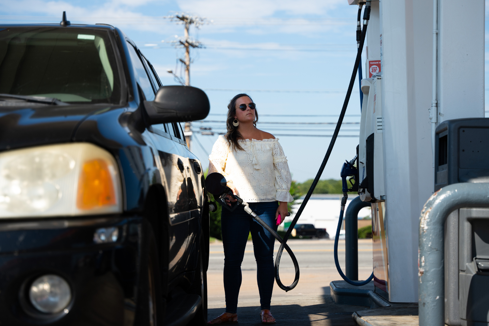 woman at gas pump looking alert and holding pepper spray