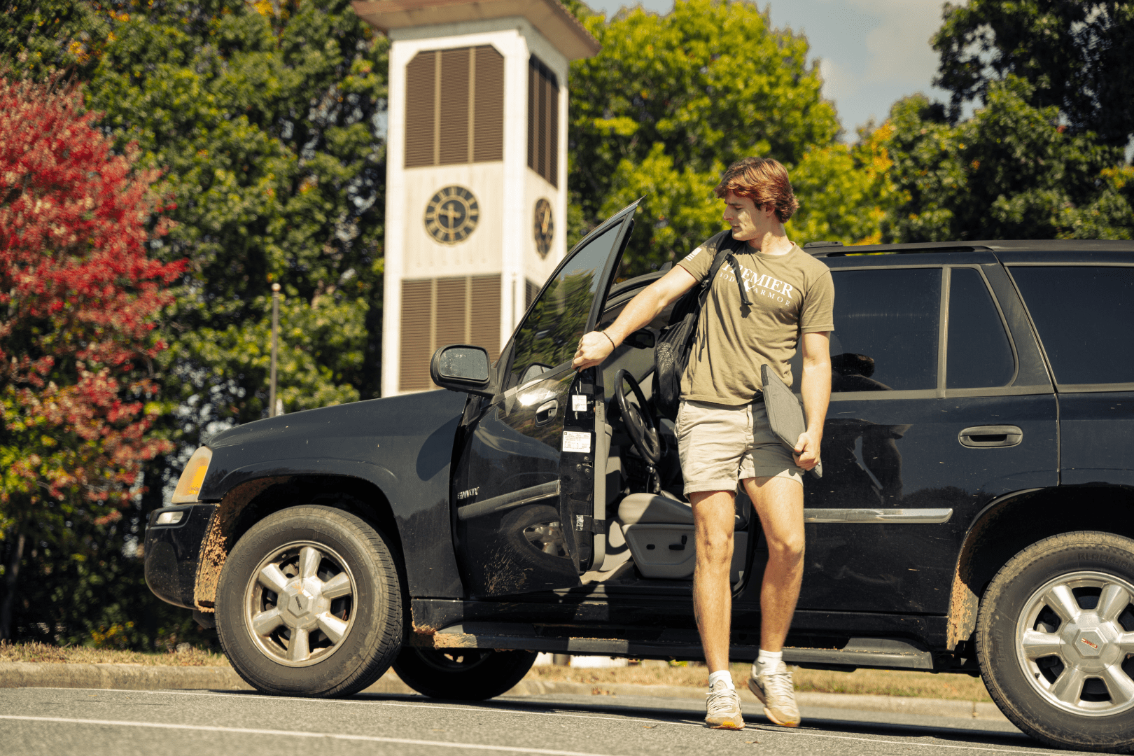 student getting out of a car on campus with laptop case