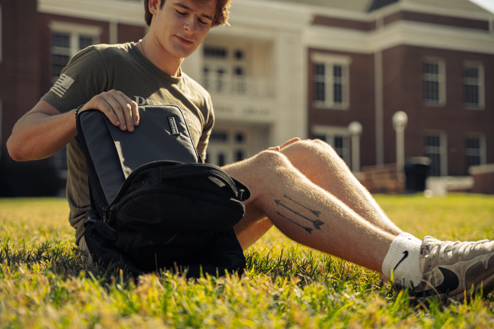 student putting bulletproof laptop case in backpack on college campus