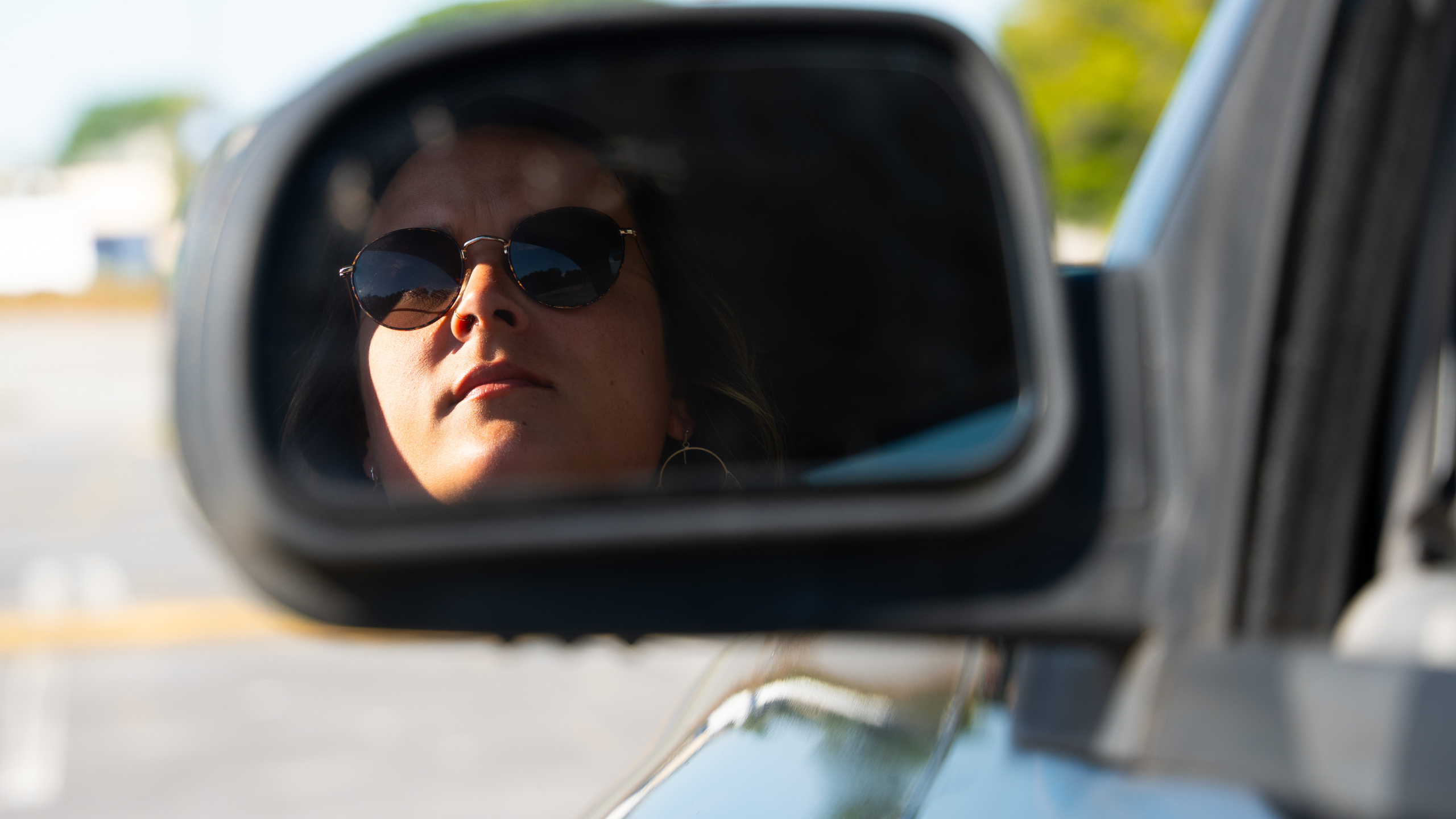woman looking in rear view mirror before getting out of the car