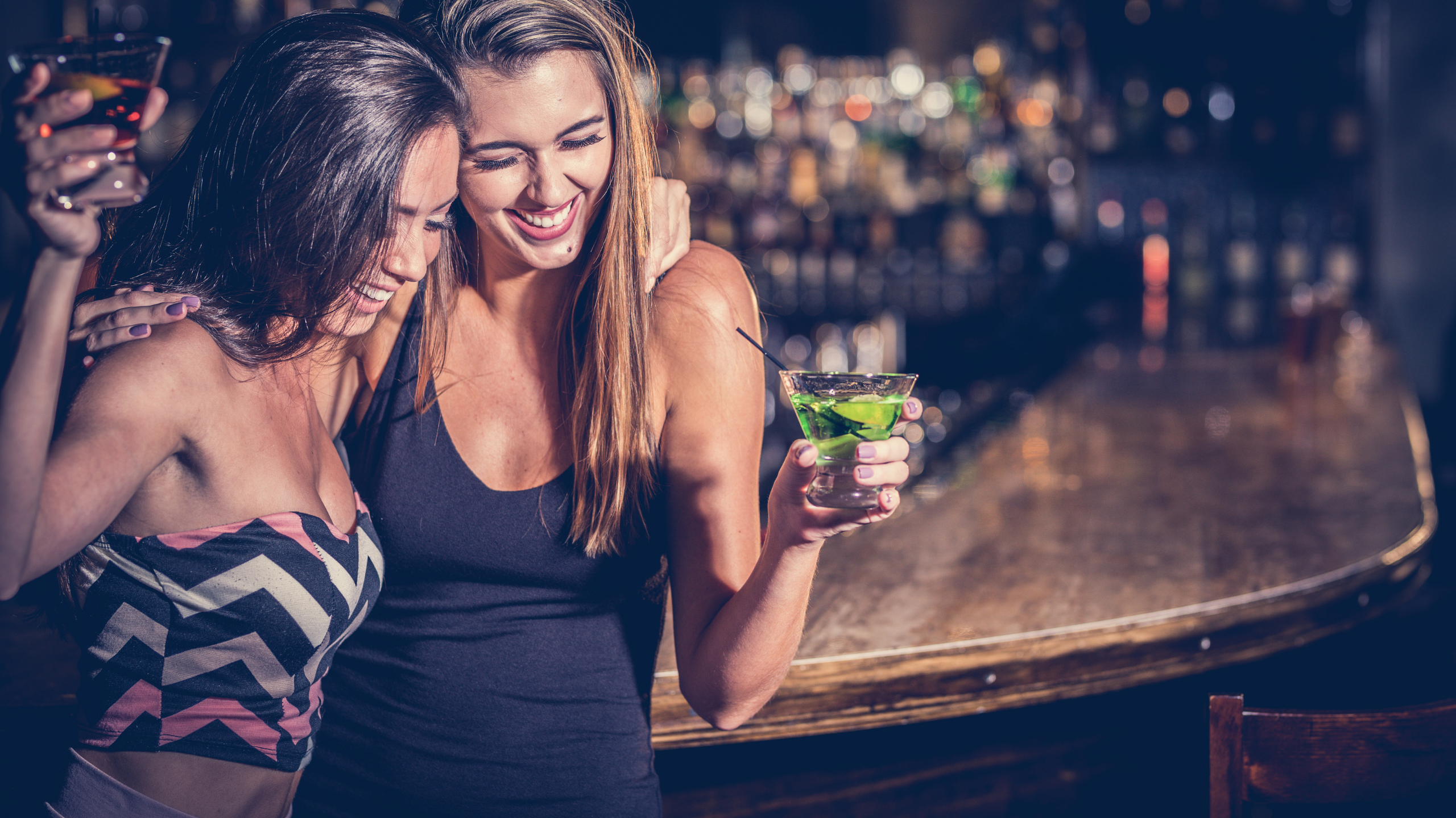 two girls with cocktails at bar