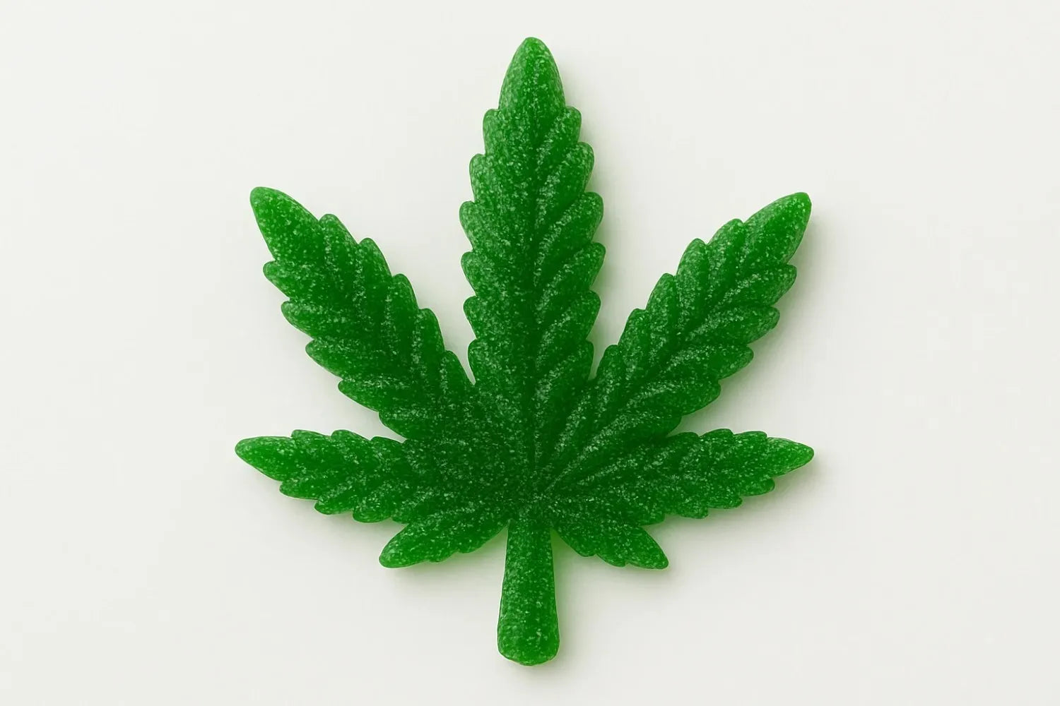 Green gummy candy shaped like a marijuana leaf on a white background, coated with sugar crystals.