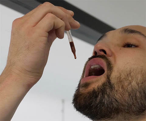 A man takes deer antler velvet by inserting liquid drops under his tongue.