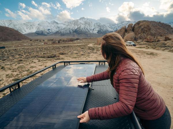 A Woman Wearing a Red Coat Is Installing BougeRV’s Hail-resistant Flexible Yuma CIGS solar panels on the RV
