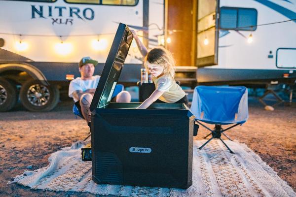 A little girl taking goods out of a BougeRV’s 12V portable camping fridge during RV camping