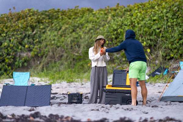 A man and woman camping using BougeRV’s portable fridge, portable power station, and portable solar panels