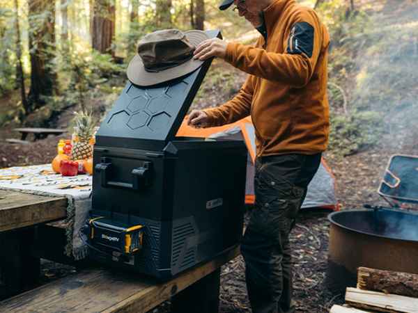 A man cooking and taking food out of the BougeRV’s electric cooler