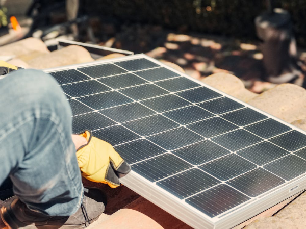 A man mounting a solar panel on the roof