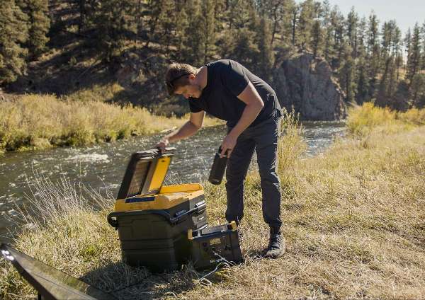 A man opening up a BougeRV’s 12V portable fridge that comes with wheels