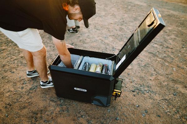 A man taking food and drinks out of BougeRV’s 12V fridge