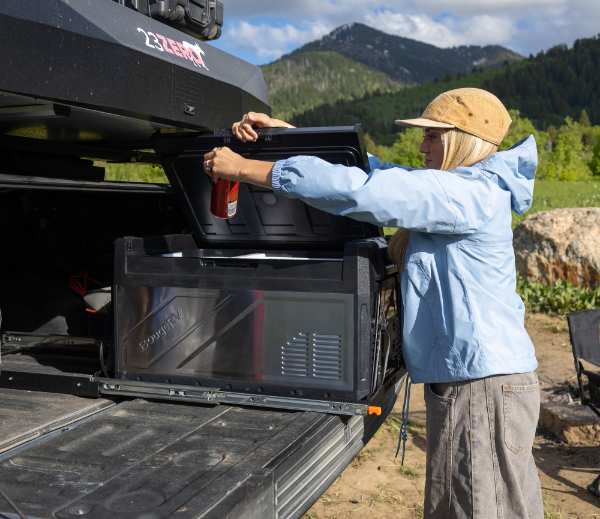 A woman taking a drink out of a BougeRV portable fridge in the trunk.png