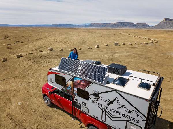 A woman titling portable solar panels on the RV roof