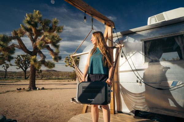 A woman using BougeRV's portable power station for electricity during RV living