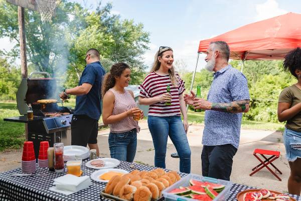 Friends chatting, grilling, and eating at tailgate parties