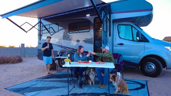 Friends have dinner in front of their with two dogs sitting under the table