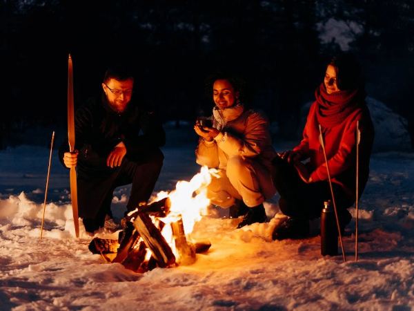 Friends warming themselves around a campfire on a winter night