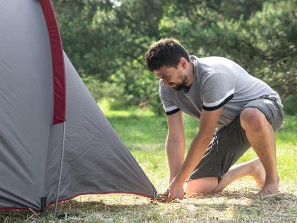 Young man setting up a tent in a Camp