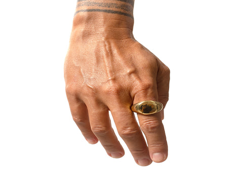 tattooed hands wearing a rugged ring with a stone at the center.