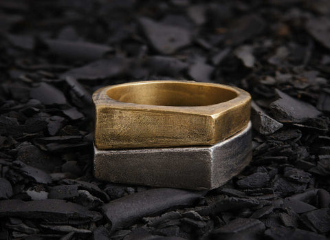 a jewelry ring having the style of stacked metal flat-faced rings placed on the ground