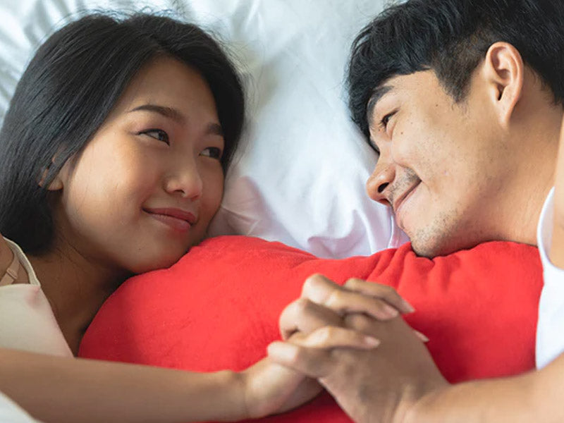 couple holding hands on bed